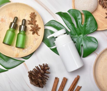 Cosmetic bottle containers packaging with green herbal leaves, Blank label for organic branding mock-up, Natural skincare beauty product concept.